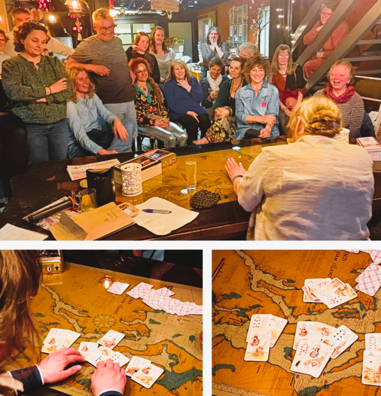 Kaartdemonstratie – live legging en interactie met het publiek Een vrouw zit aan een grote tafel, omringd door geïnteresseerde deelnemers. Ze legt kaarten uit in een live demonstratie.